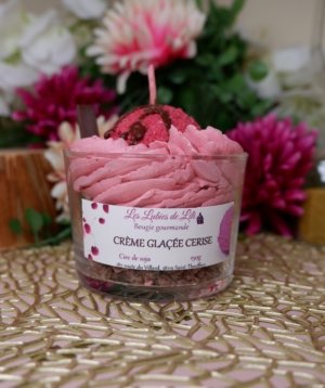 Bougie chantilly rose avec une boule de glace rouge, un coulis marron et un crumble en fond de pot