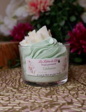 bougie chantilly vert claire avec une fleur représentant une edelweiss blanche sur le dessus