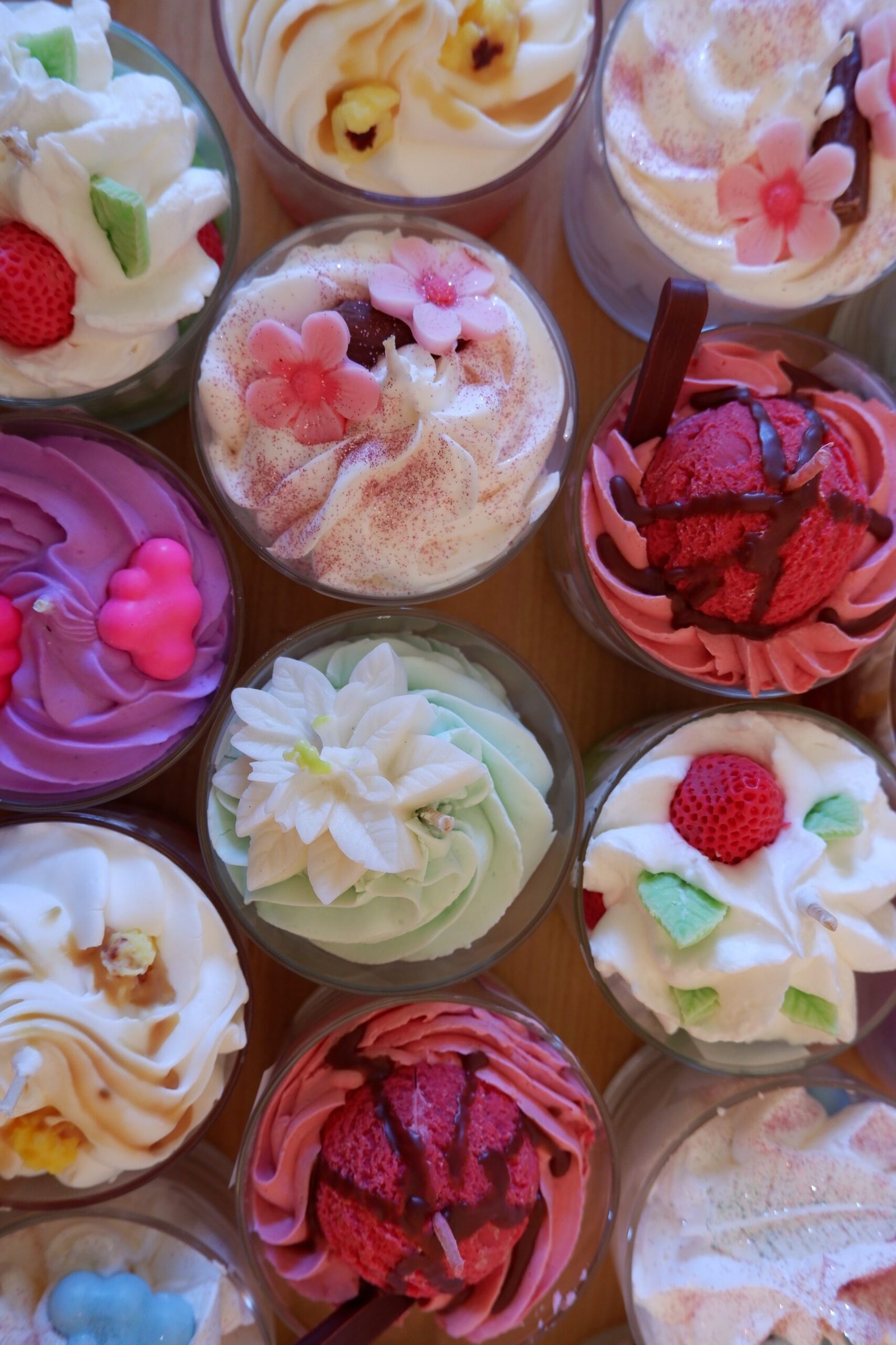 Collection de bougies gourmandes artisanales parfumées avec chantilly et décorations variées, idéales pour la décoration et les idées cadeaux