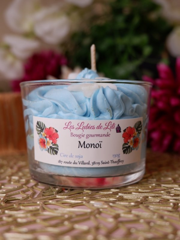 Bougie chantilly Monoï aevc une chantilly bleu, un fond blanc avec des paillettes et des fleur blanche sur le dessus