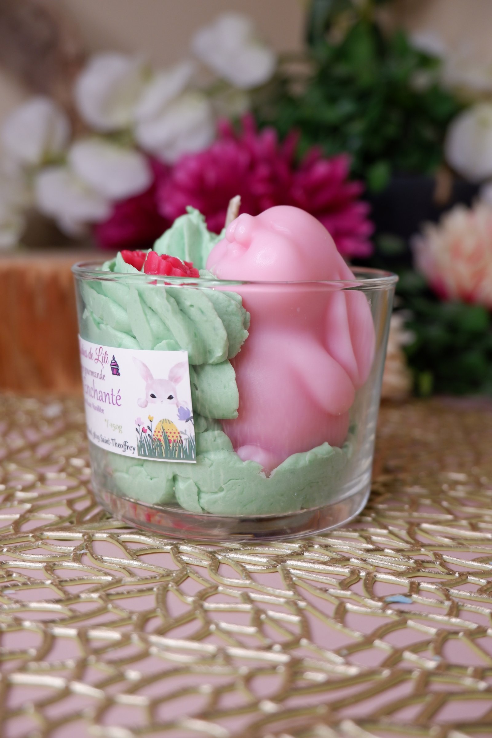 Bougie de Pâques artisanale avec un lapin rose, chantilly verte et fleurs rouges, senteur rose vanillée, dans un pot en verre, parfaite pour une décoration festive de table