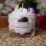 Bougie chantilly, avec cumble marron au fond, puis chantilly blance avec des oeufs de paques marron un lapin blanc et un macaron violet
