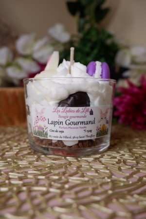 Bougie chantilly, avec cumble marron au fond, puis chantilly blance avec des oeufs de paques marron un lapin blanc et un macaron violet