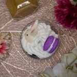 Bougie chantilly, avec cumble marron au fond, puis chantilly blance avec des oeufs de paques marron un lapin blanc et un macaron violet