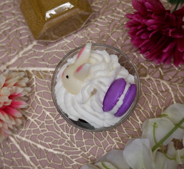Bougie chantilly, avec cumble marron au fond, puis chantilly blance avec des oeufs de paques marron un lapin blanc et un macaron violet