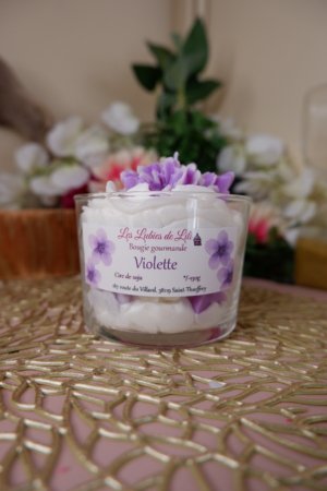 Bougie artisanale gourmande au parfum violette avec chantilly blanche et fleurs violettes en décoration, fabriquée à la main.