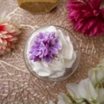 Bougie artisanale gourmande au parfum violette avec chantilly blanche et fleurs violettes en décoration, fabriquée à la main.