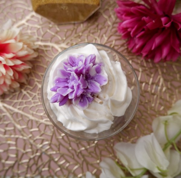 Bougie artisanale gourmande au parfum violette avec chantilly blanche et fleurs violettes en décoration, fabriquée à la main.
