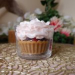 Bougie parfum cheesecake aux fruits rouges, avec une base biscuit, une couche de chantilly rose pâle et des fruits rouges à l'interieur