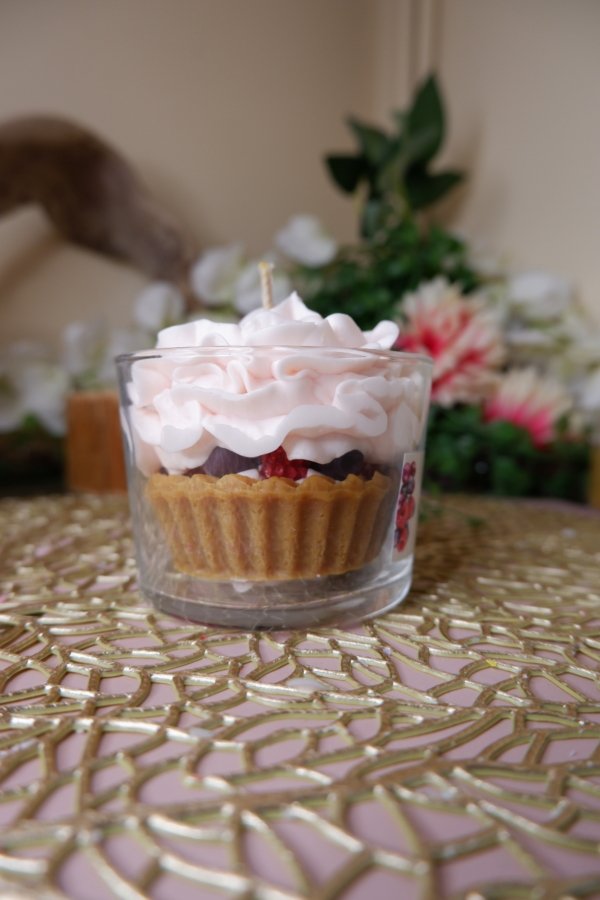 Bougie parfum cheesecake aux fruits rouges, avec une base biscuit, une couche de chantilly rose pâle et des fruits rouges à l'interieur